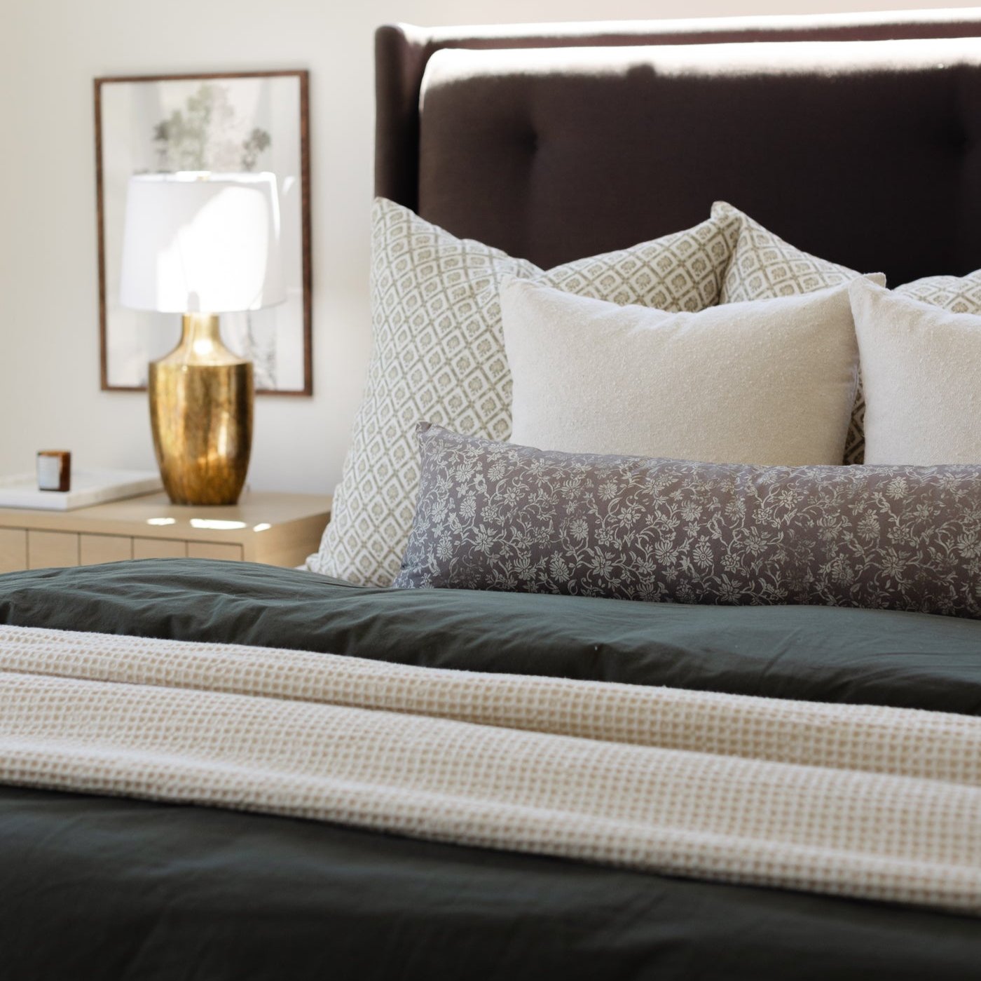 Ivory waffle-textured blanket draped across a bed with patterned pillows.