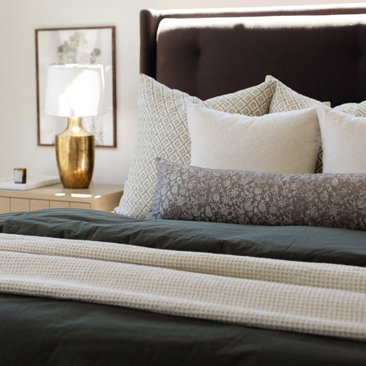 Ivory waffle-textured blanket draped across a bed with patterned pillows.