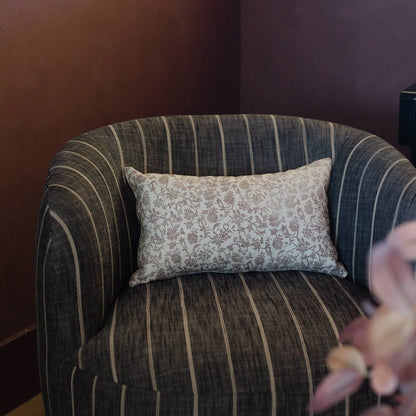 Rectangular lumbar pillow with beige floral damask pattern displayed on striped upholstered chair.