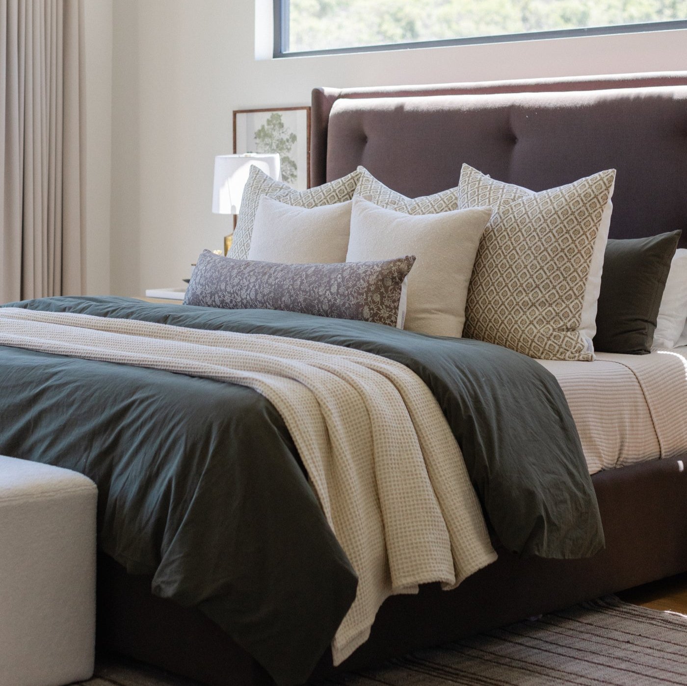 Ivory waffle-textured blanket draped across a bed with dark bedding and decorative pillows.