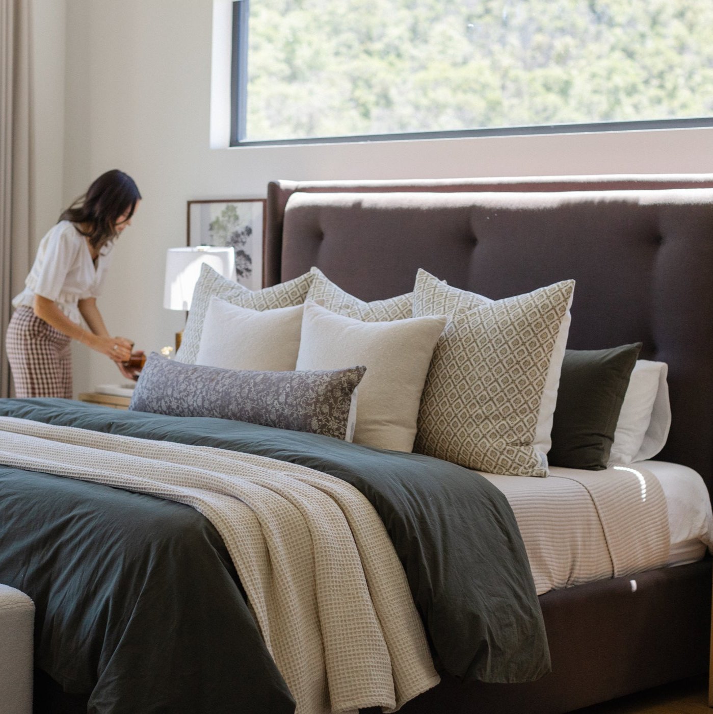 Ivory waffle-textured blanket draped across a bed with black comforter and decorative pillows.