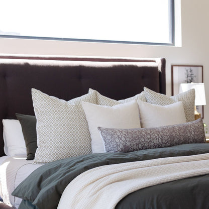 Ivory waffle-textured blanket layered on a bed with patterned and solid pillows.
