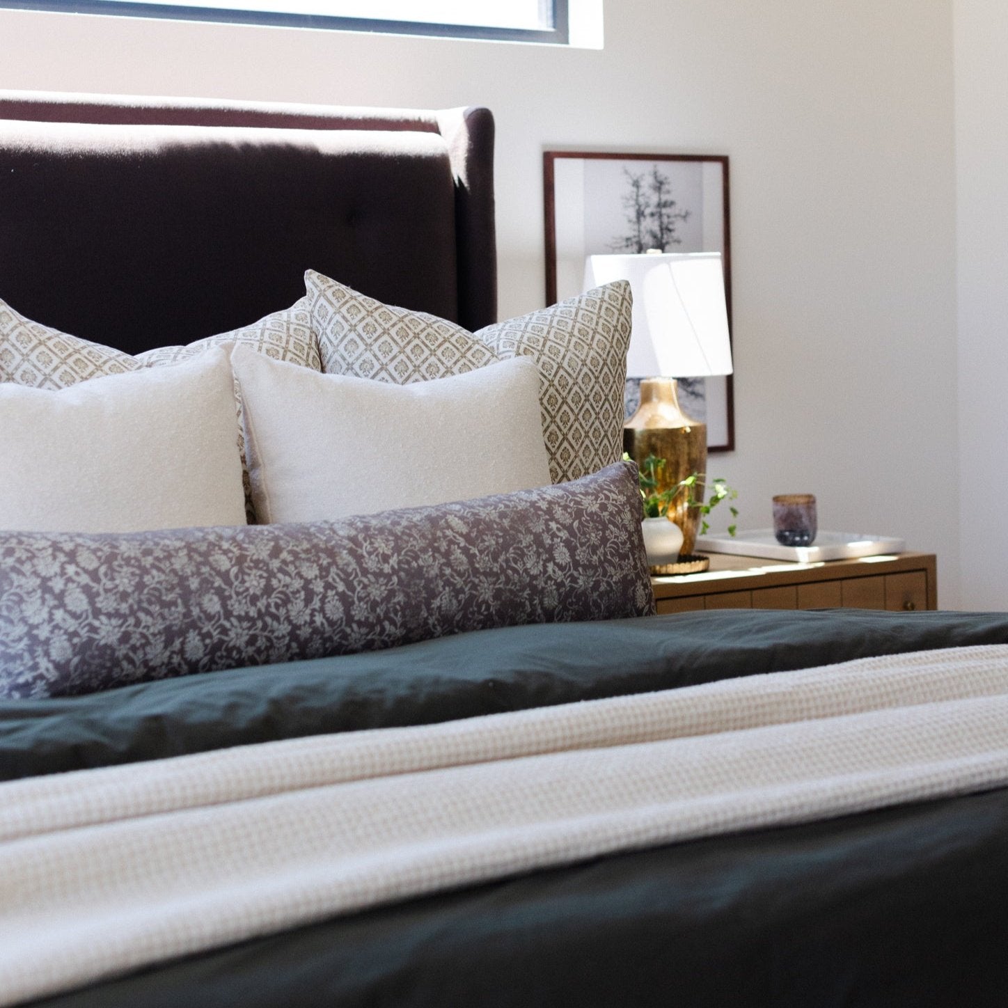 Ivory waffle-textured blanket draped across a bed with patterned pillows.