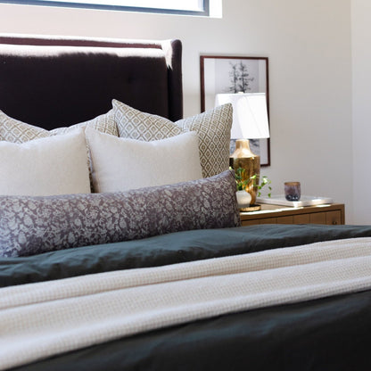 Ivory waffle-textured blanket draped across a bed with patterned pillows.
