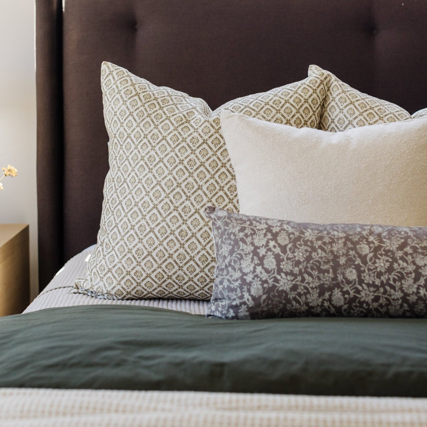 Gretta lumbar pillow with tan and cream geometric diamond pattern displayed on bed with coordinating pillows and bedding.