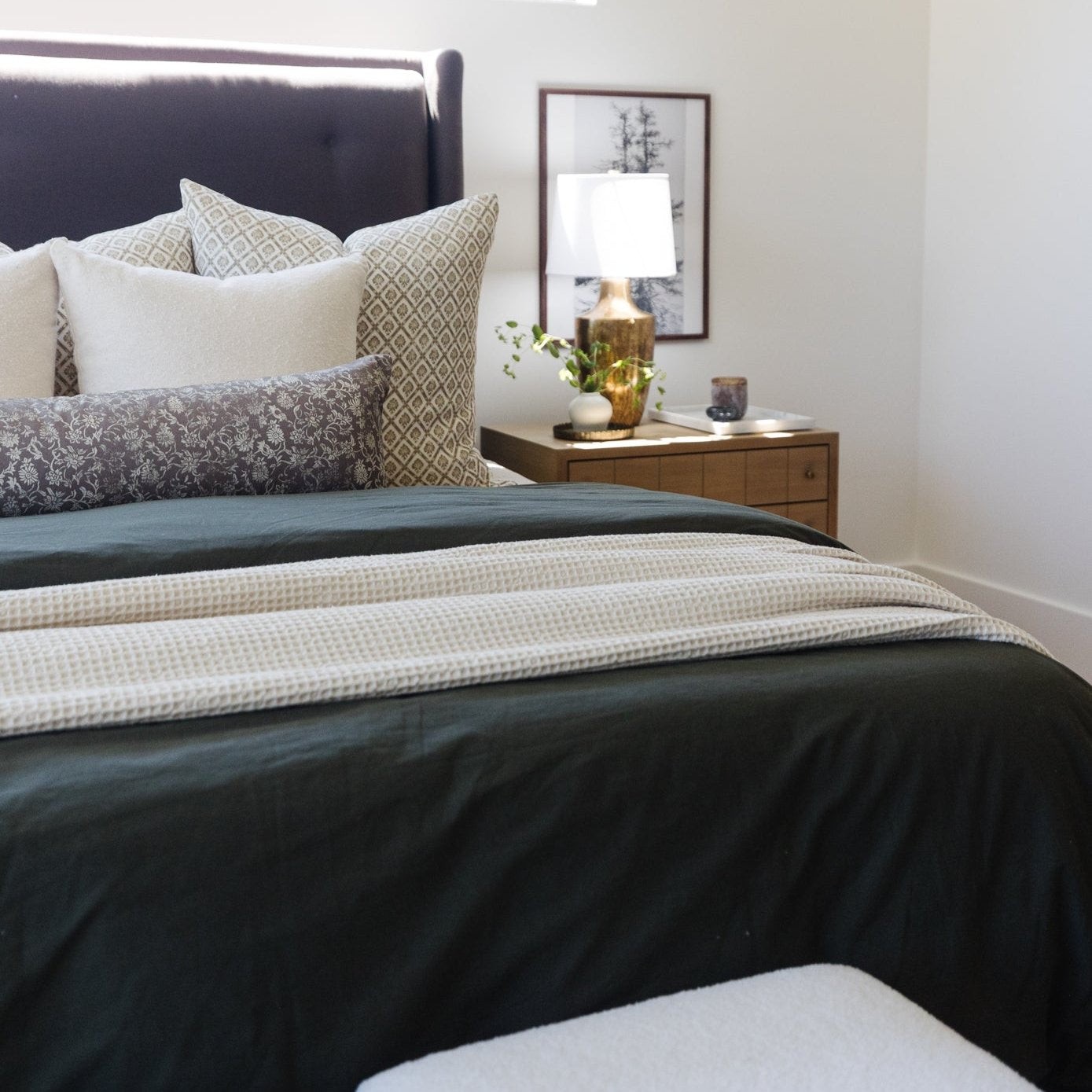 Ivory waffle-textured blanket draped across a bed with dark bedding.
