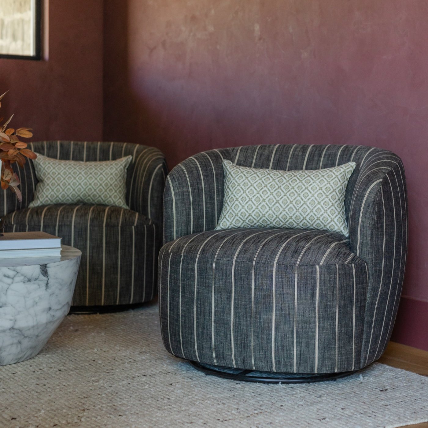 Cream linen lumbar pillow with geometric diamond pattern displayed on striped armchair.