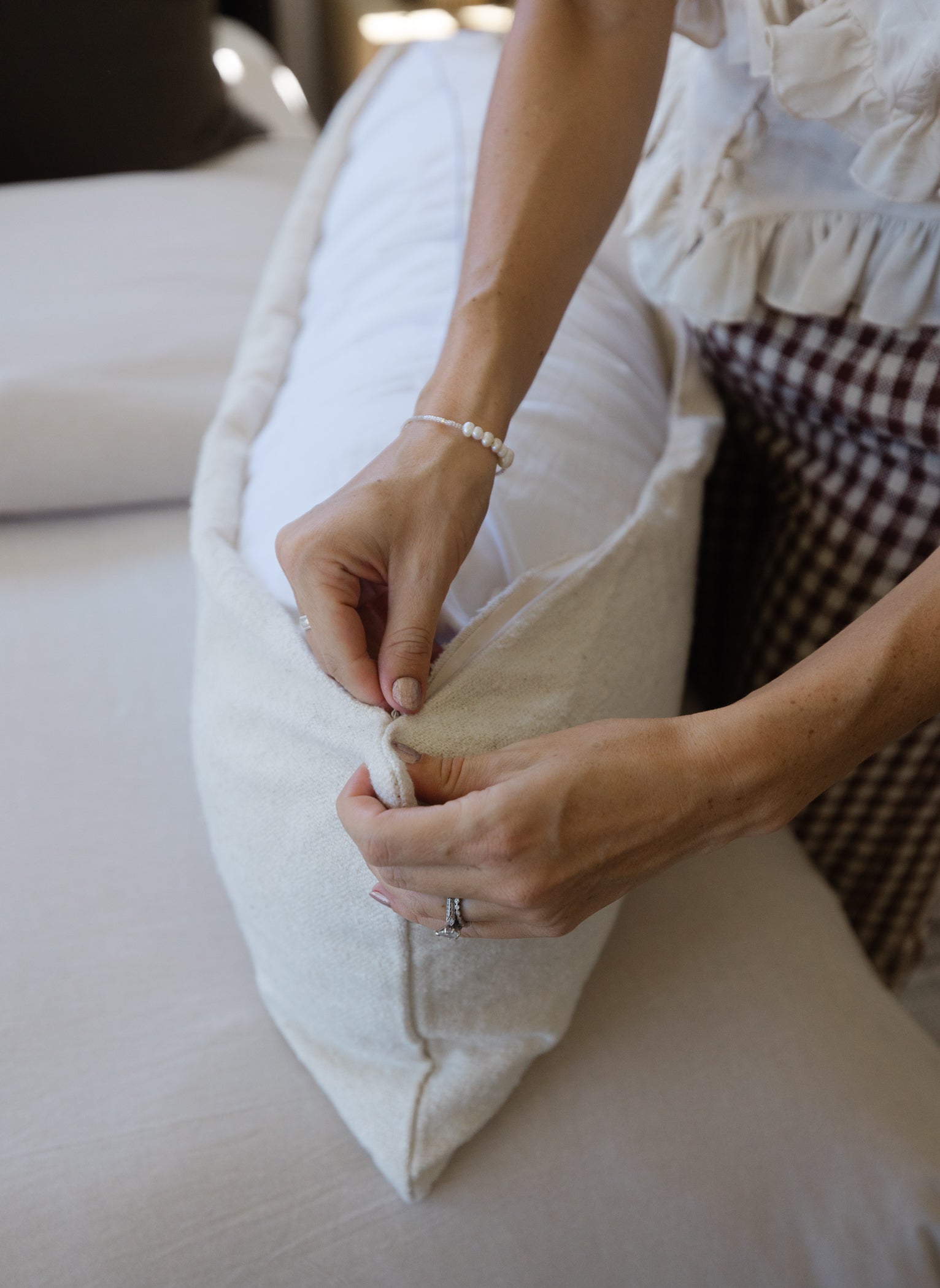 Off-white boucle pillow with textured fabric being held in hands, showing cushion construction.
