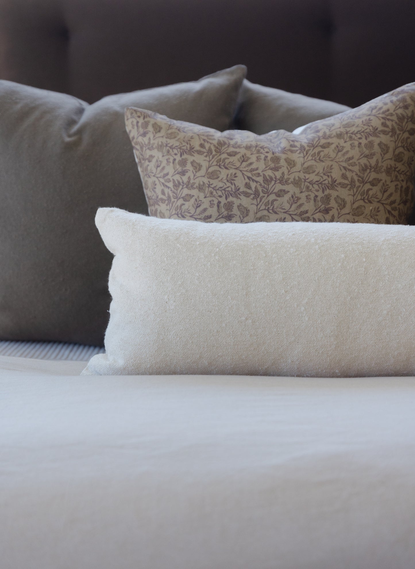 Off-white boucle lumbar pillow with textured weave displayed on bedding.