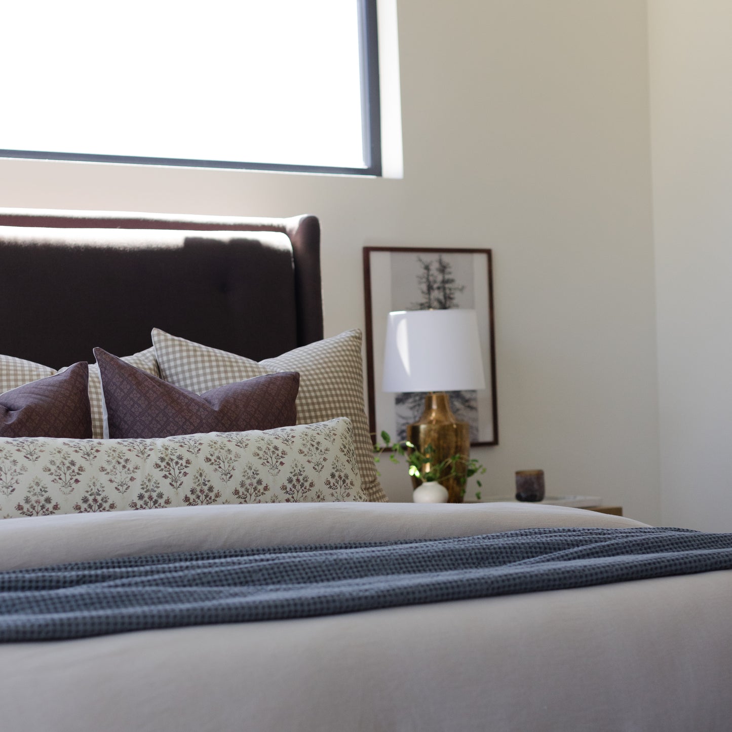 Brown and cream lumbar pillow displayed among other decorative pillows on a bed.