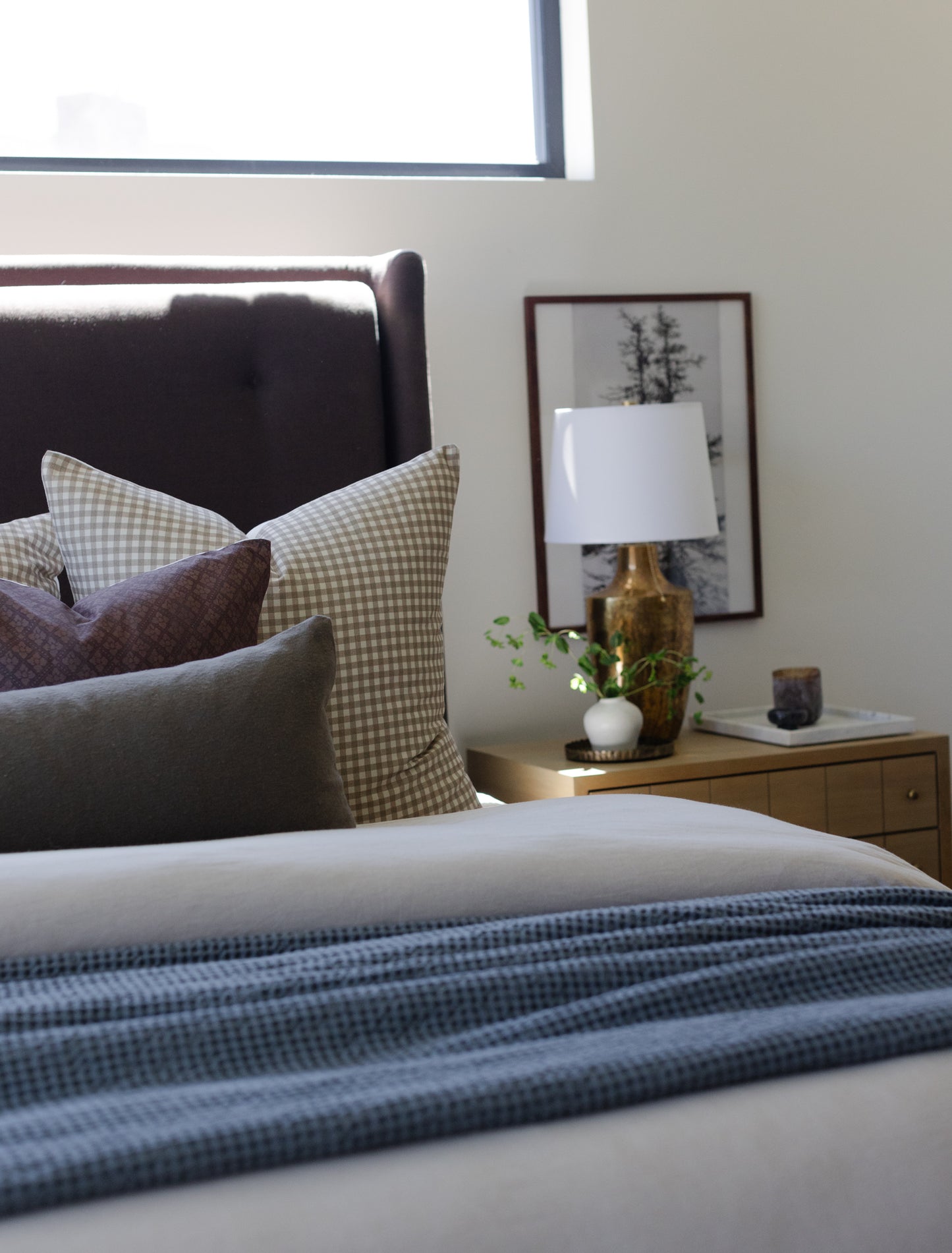 Olive green boucle pillow with textured weave displayed on bed with gingham and solid pillows.