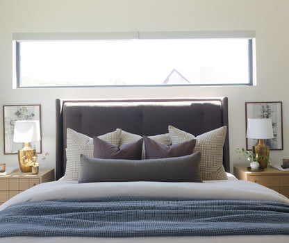 Olive green boucle lumbar pillow displayed on bed with matching decorative pillows and textured bedding.