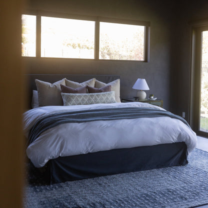 Maroon upholstered bed headboard with blue and gray decorative pillows in modern bedroom setting.