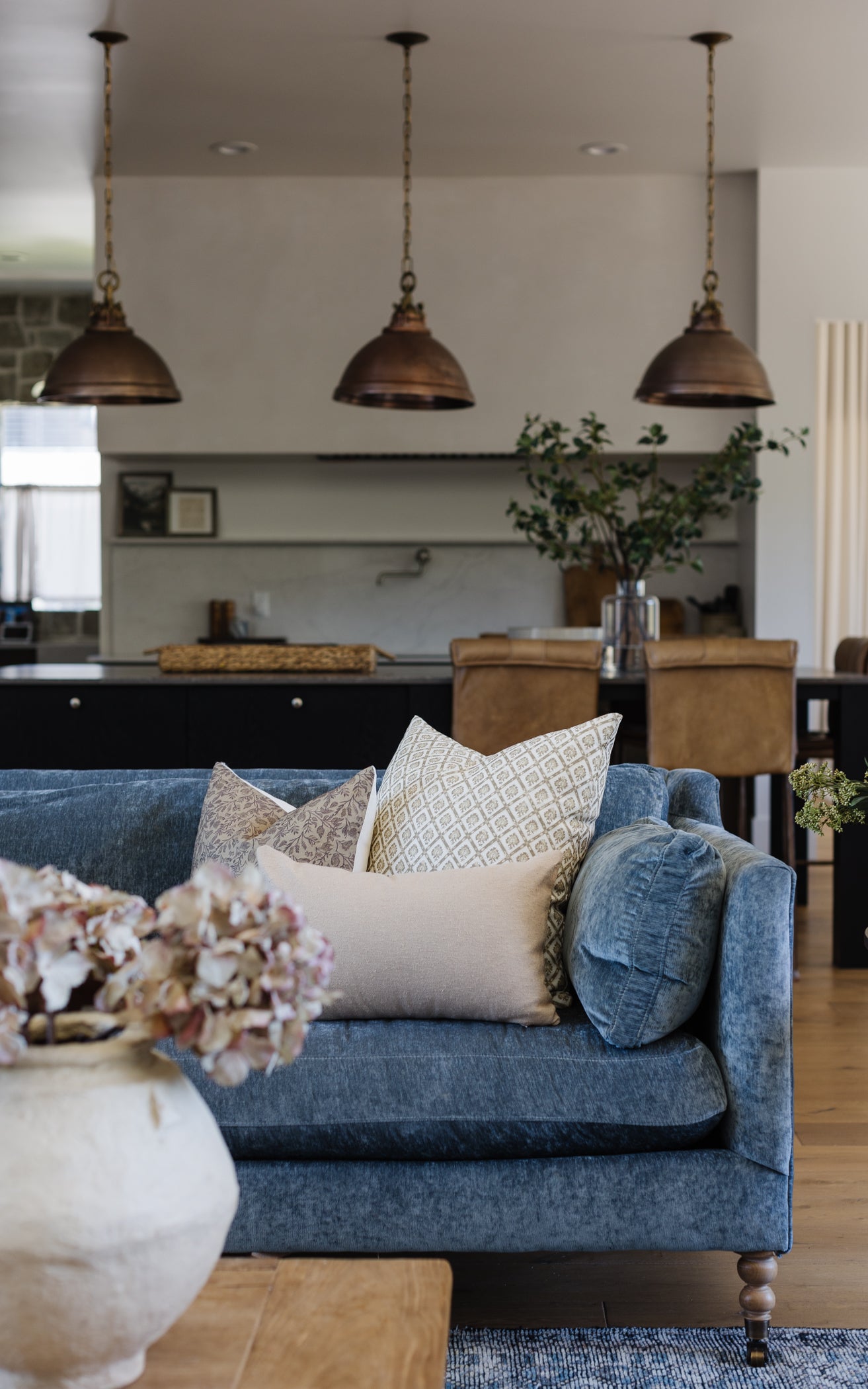 Beige boucle lumbar pillow with textured weave pattern displayed on blue sofa in living room setting.