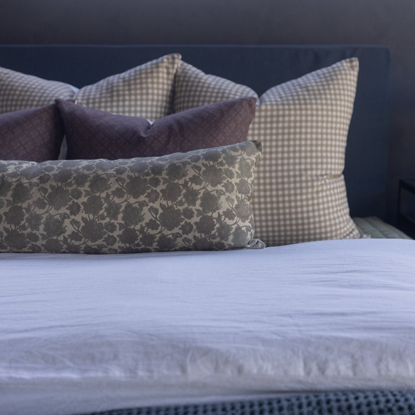 Rectangular lumbar pillow with damask pattern in gray and beige tones, displayed on bed with coordinating pillows.