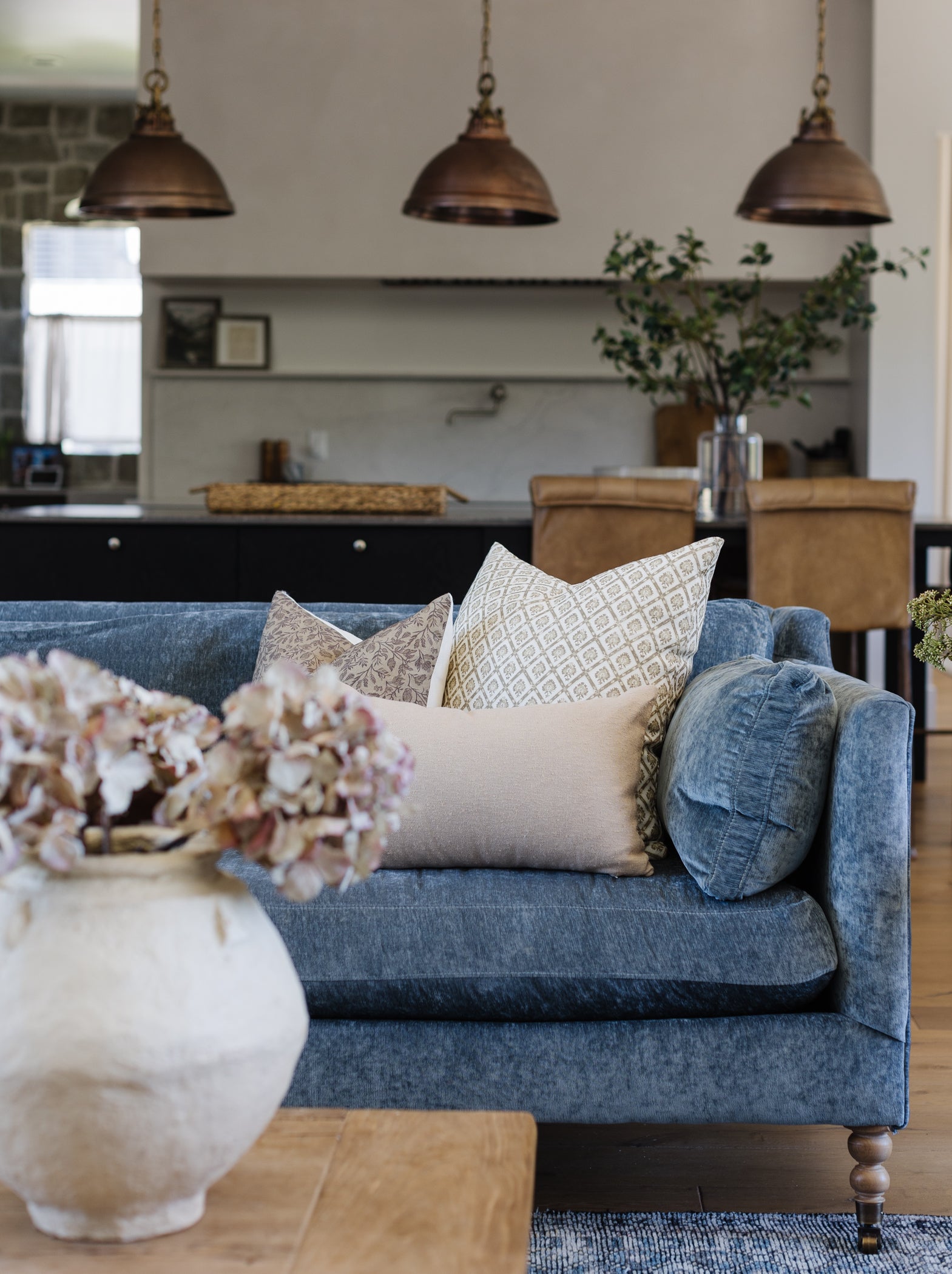 Beige boucle lumbar pillow displayed on blue upholstered sofa in living room setting.