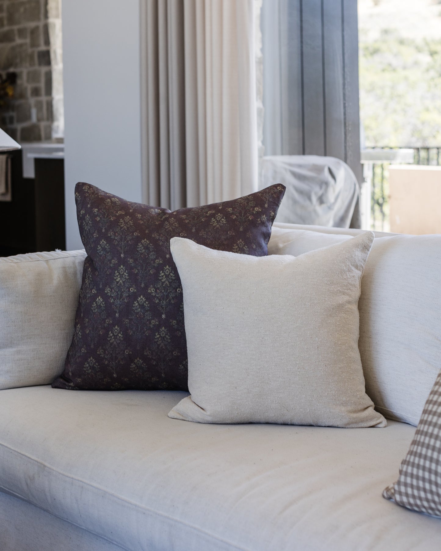 Off-white textured boucle pillow displayed on a light-colored sofa with other decorative pillows.