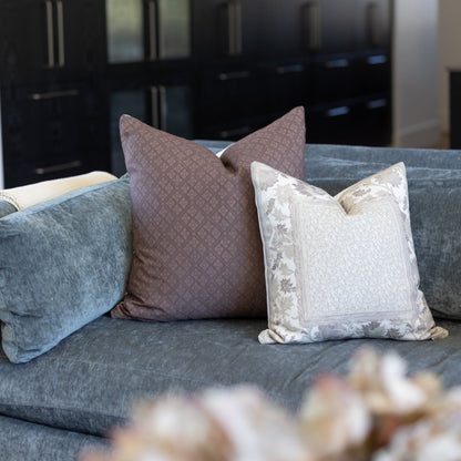 Maroon textured throw pillow displayed on gray sofa with coordinating pillows in blue and cream with floral pattern.