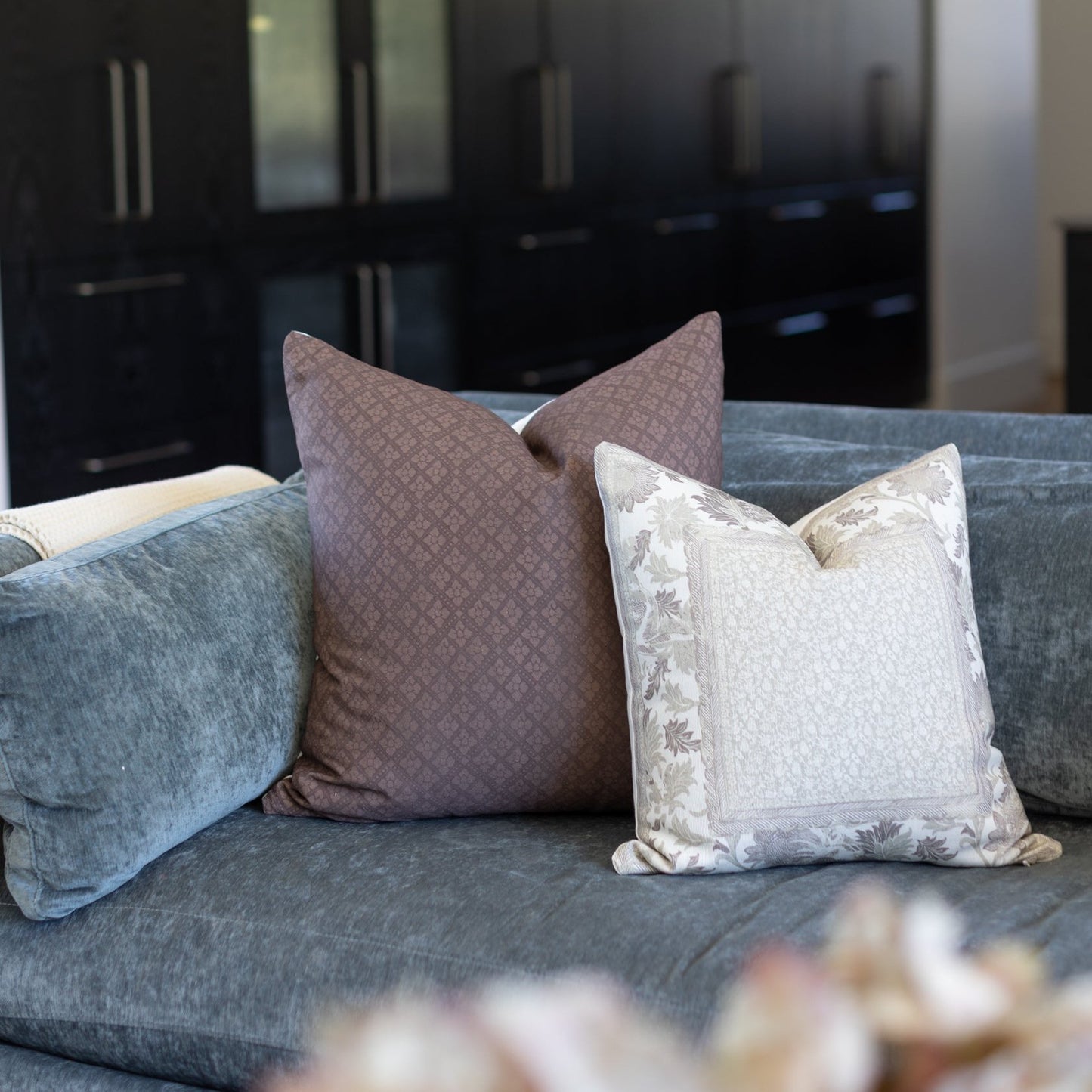 Brown corduroy throw pillow with quilted pattern displayed on gray upholstered sofa.