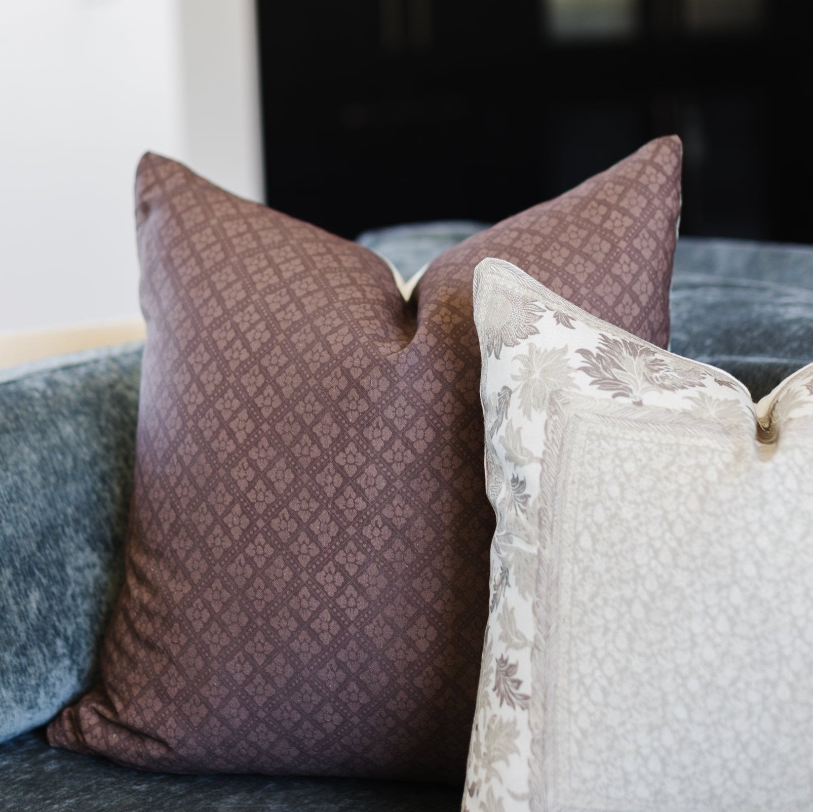 Maroon textured pillow with small geometric pattern displayed on a sofa.
