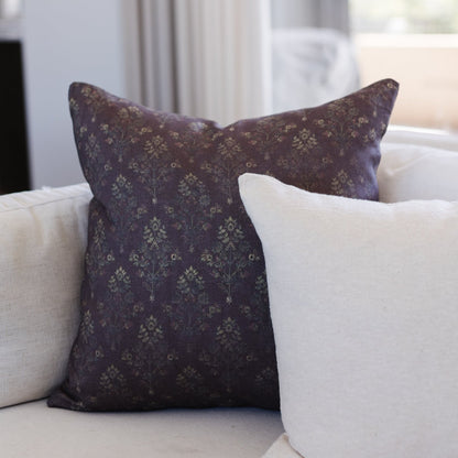 Dark burgundy linen pillow with subtle damask pattern, displayed on a neutral sofa.