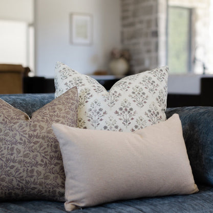 Decorative pillows with floral and solid patterns arranged on a gray upholstered sofa in a living room.