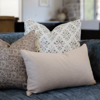 Decorative pillows in floral and solid patterns arranged on a gray upholstered sofa.