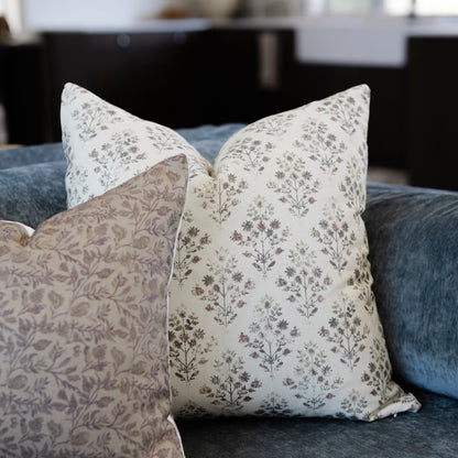 Cream and taupe floral patterned throw pillows arranged on a blue upholstered sofa.