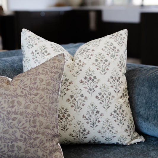 Cream and taupe floral patterned throw pillows arranged on a blue upholstered sofa.