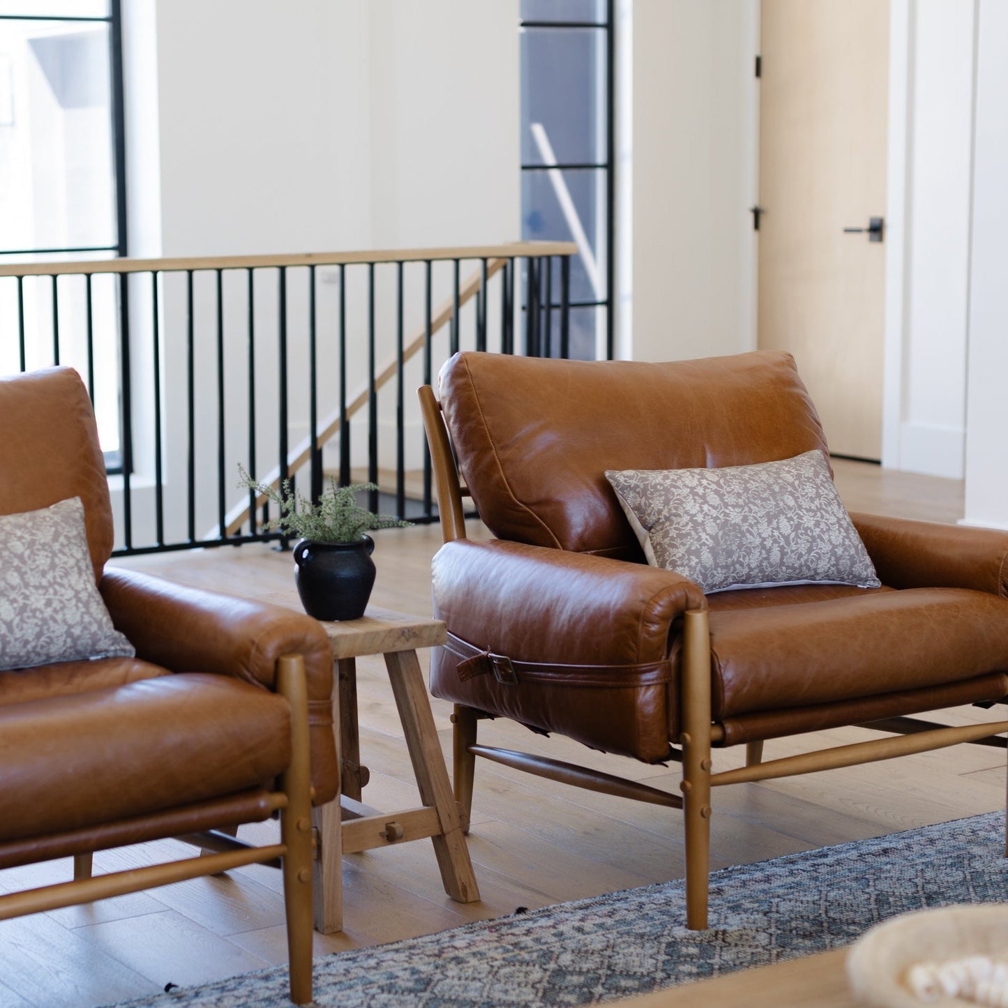 Gray and white patterned lumbar pillow displayed on a brown leather chair in a modern living room.