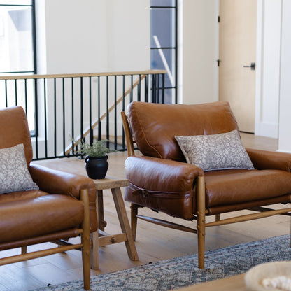 Gray and white patterned lumbar pillow displayed on a brown leather chair in a modern living room.