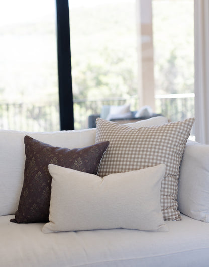 Off-white boucle lumbar pillow displayed on a white sofa with coordinating decorative pillows.