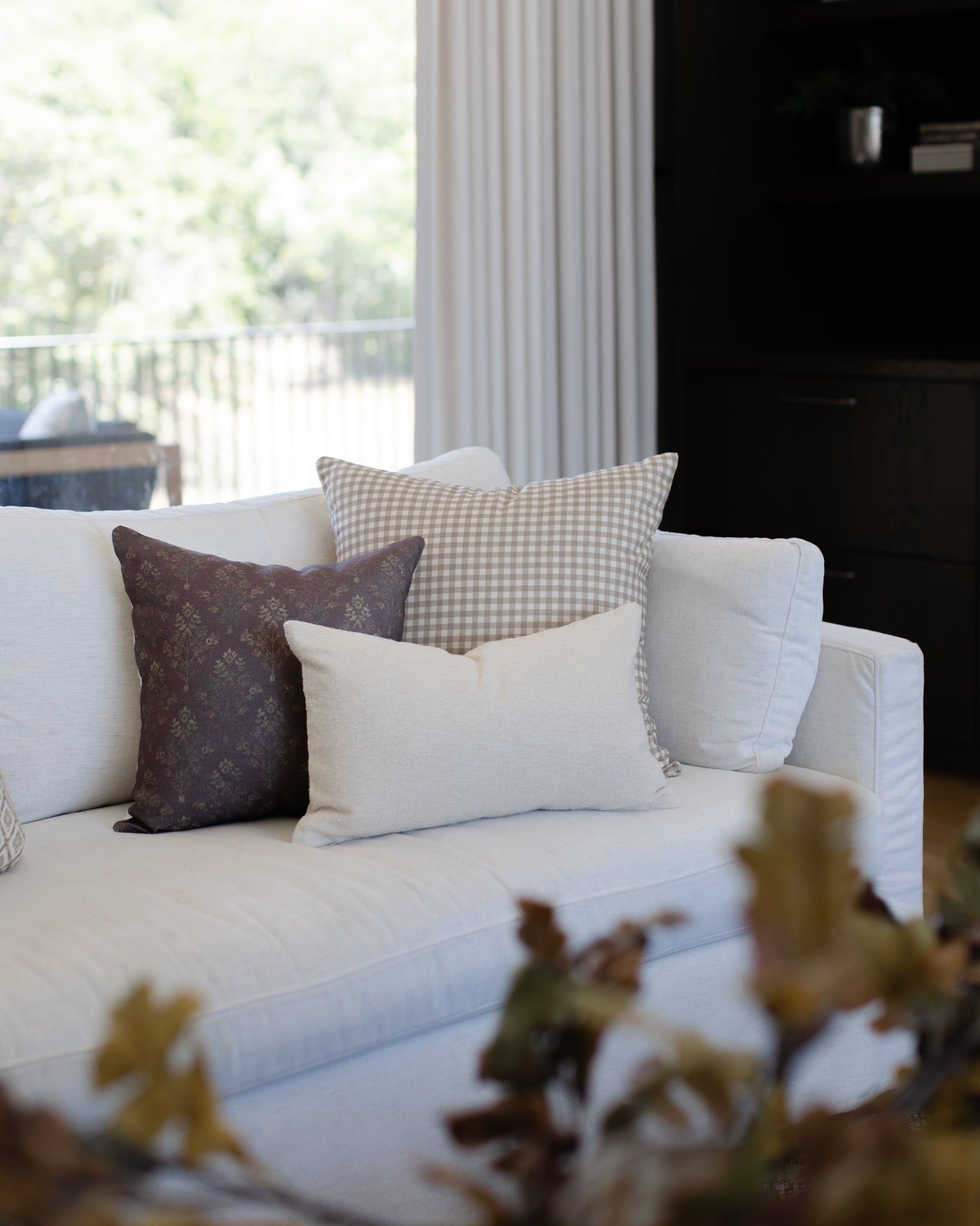 Off-white boucle textured lumbar pillow displayed on a sofa with coordinating decorative pillows.