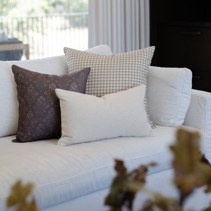 Dark brown damask linen pillow styled with gingham and cream pillows on a white sofa.