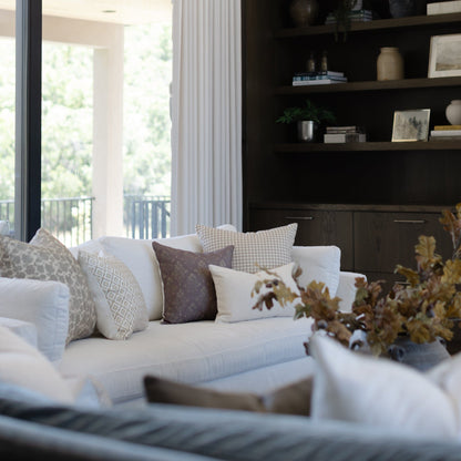 Tan and white gingham patterned throw pillow on light gray sofa with coordinating pillows.