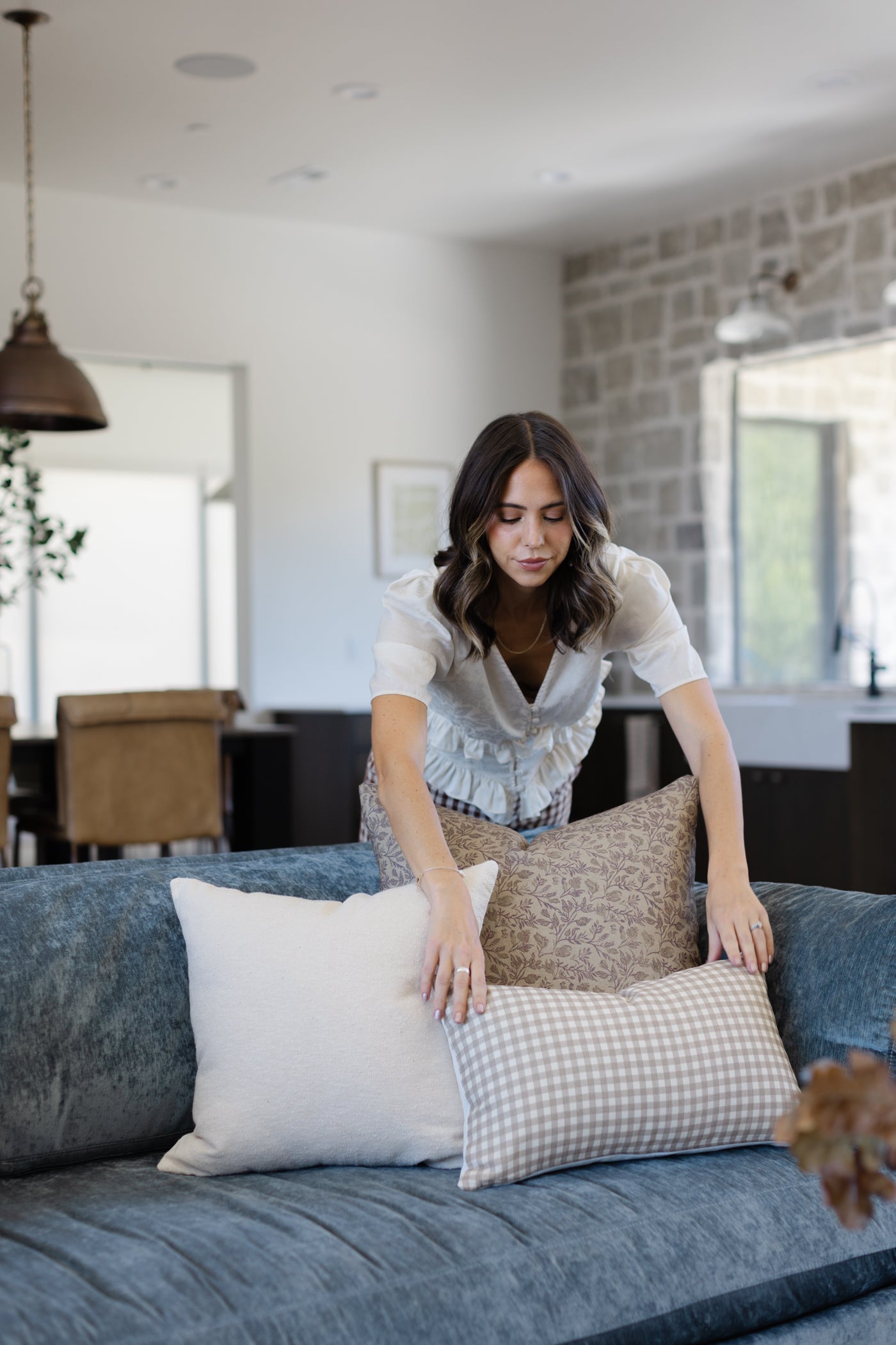 Off-white boucle textured pillow displayed on a blue sofa alongside patterned pillows in a modern living room.