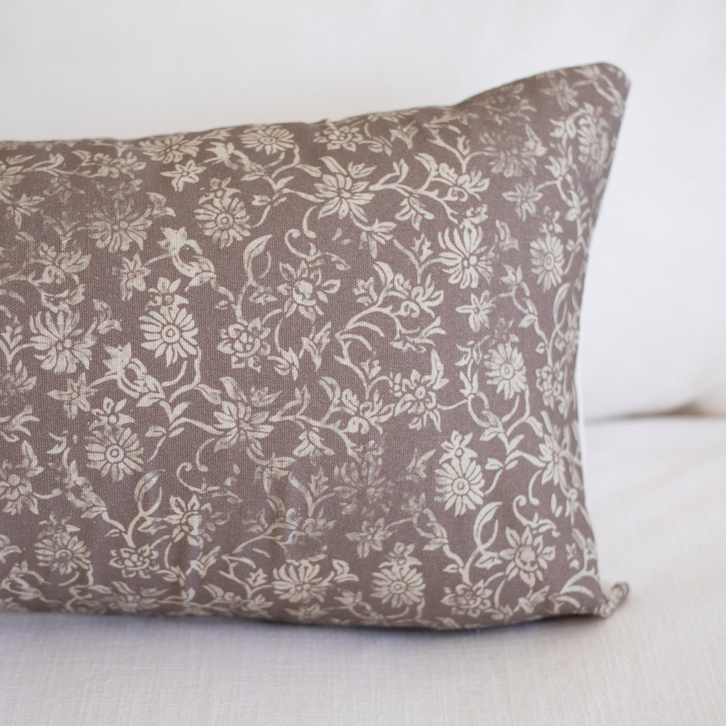 Rectangular lumbar pillow with taupe fabric featuring cream floral and leaf pattern throughout.