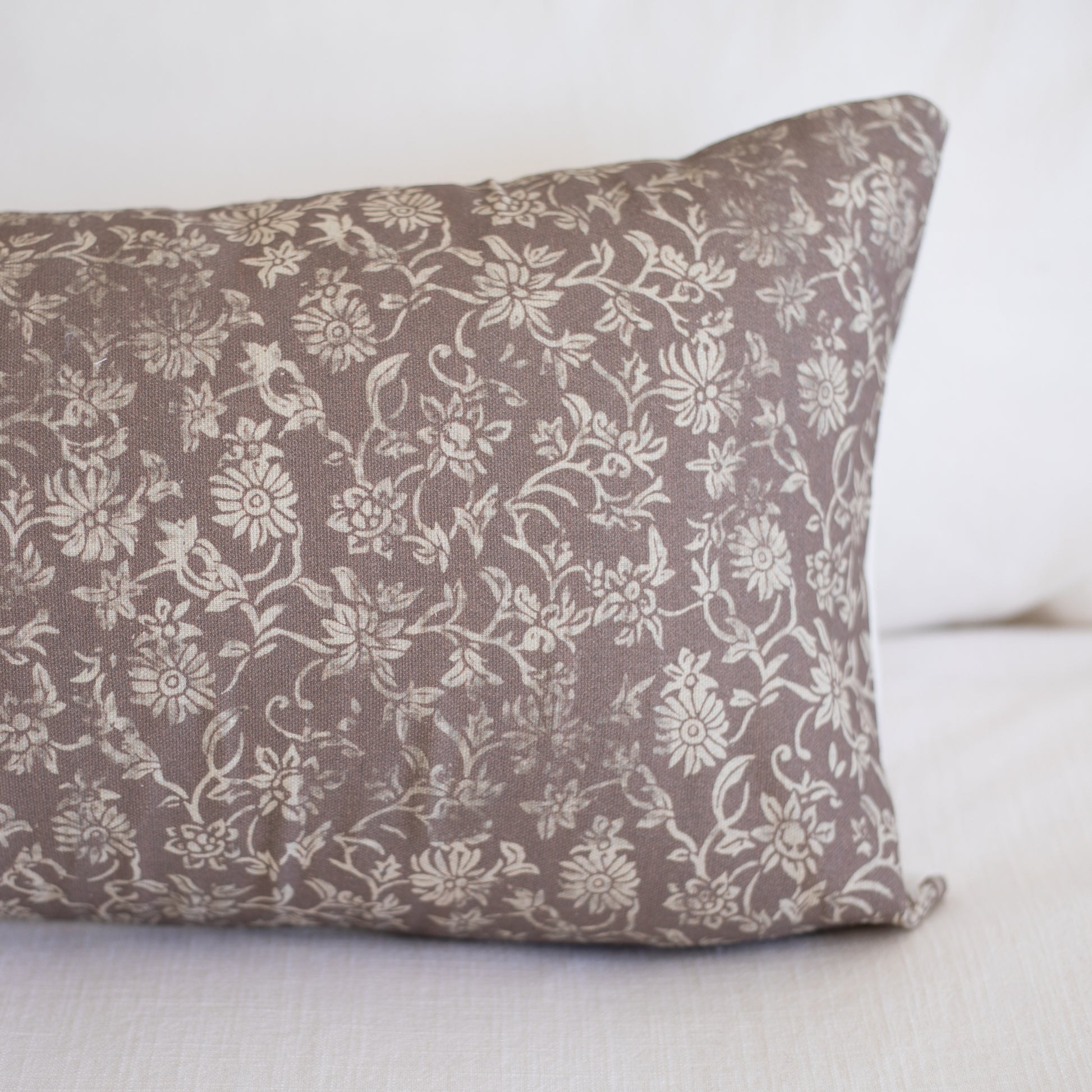 Rectangular lumbar pillow with taupe fabric featuring cream floral and leaf pattern throughout.