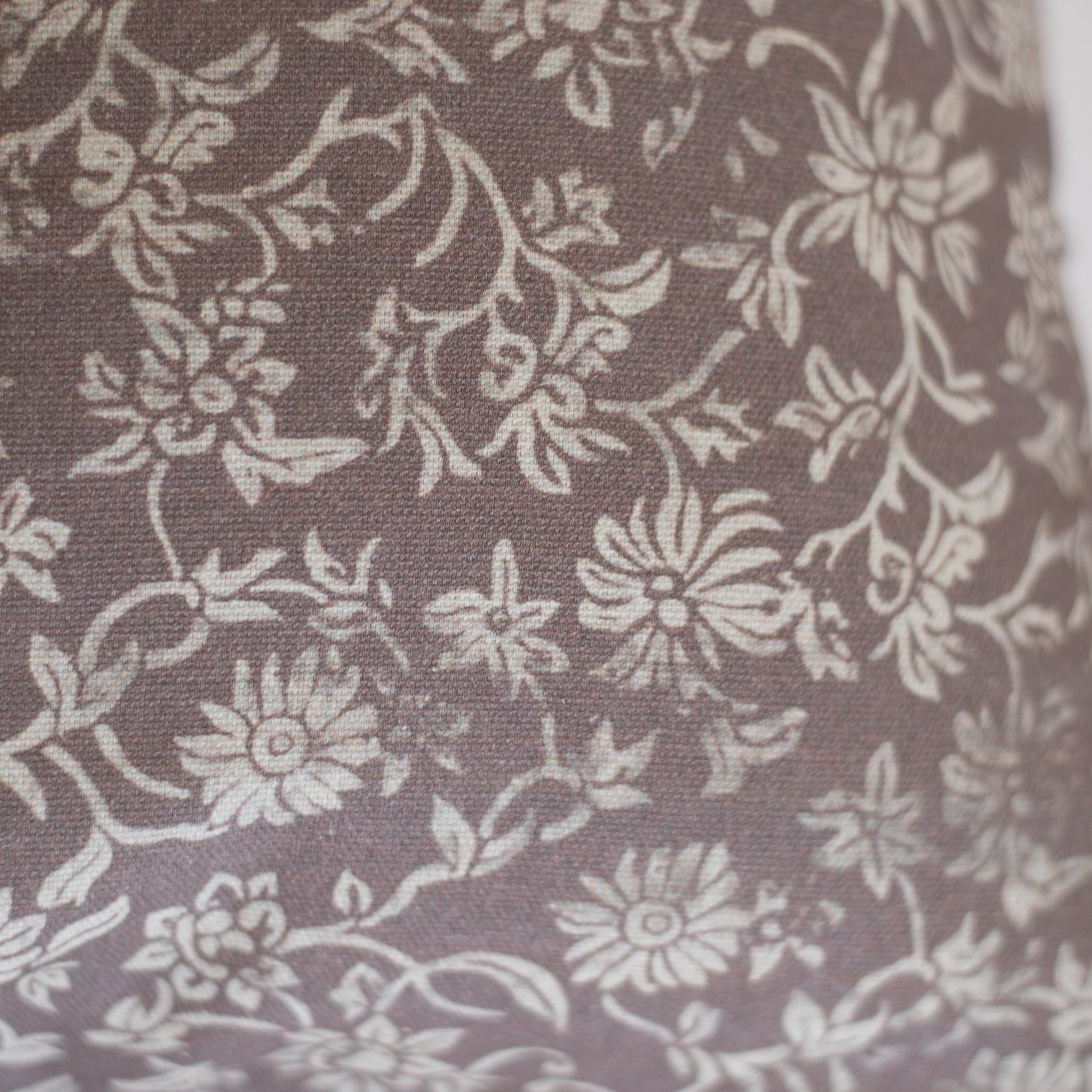 Taupe lumbar pillow with cream floral and leaf damask pattern on woven fabric.