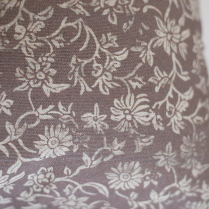 Taupe lumbar pillow with cream floral and leaf damask pattern on woven fabric.