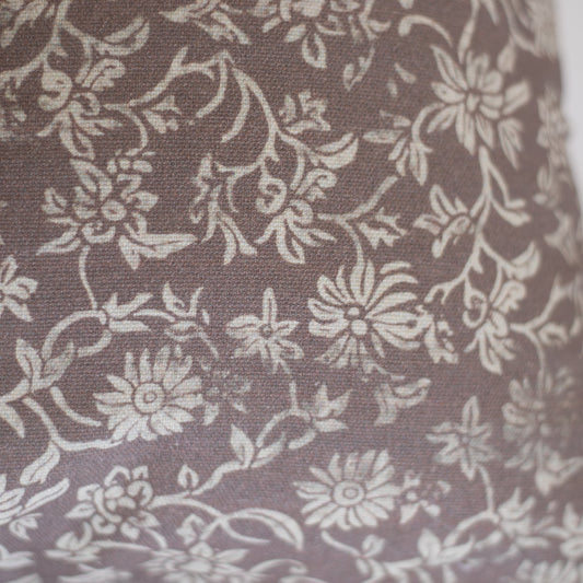 Taupe lumbar pillow with cream floral and leaf damask pattern on woven fabric.