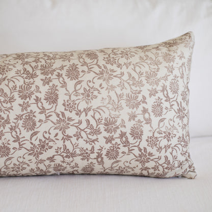 Rectangular pillow with tan linen fabric featuring a dense brown floral and vine pattern throughout.