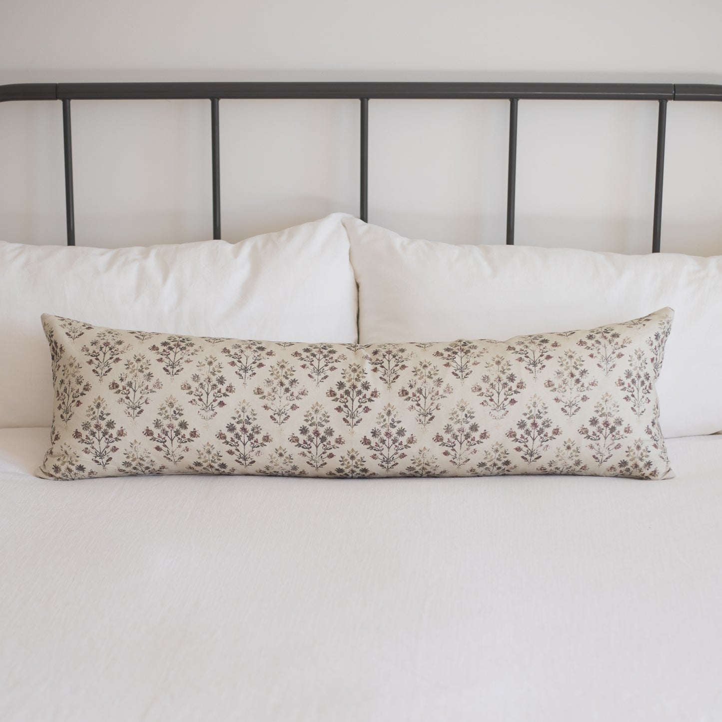 Rectangular lumbar pillow with cream and taupe damask pattern, placed on white bedding.