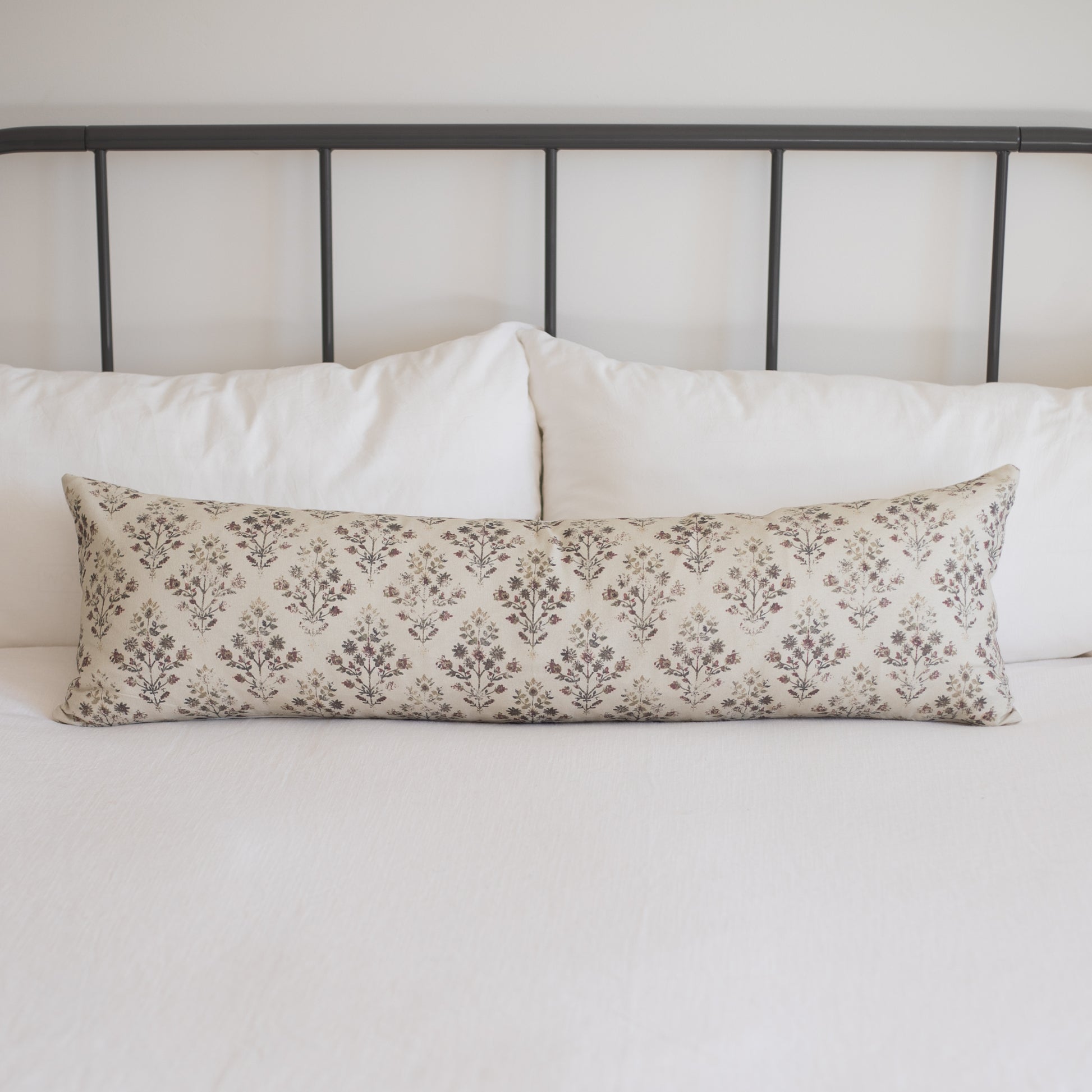 Rectangular lumbar pillow with cream and taupe damask pattern, placed on white bedding.