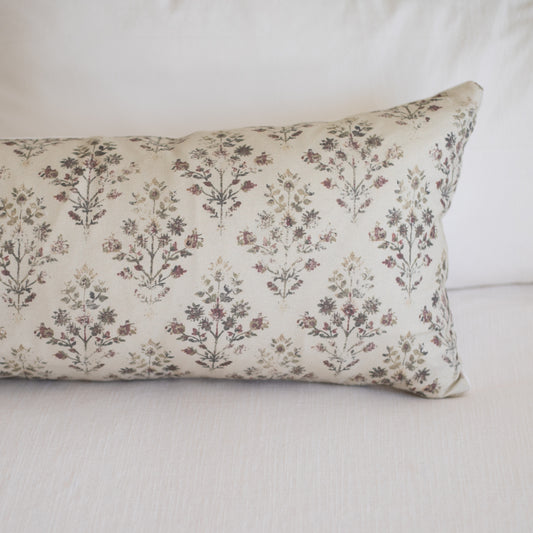 Rectangular lumbar pillow with cream linen fabric printed with small burgundy and brown botanical flowers in repeating patter