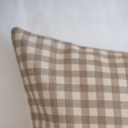Tan and white gingham patterned pillow with visible texture and piping detail.