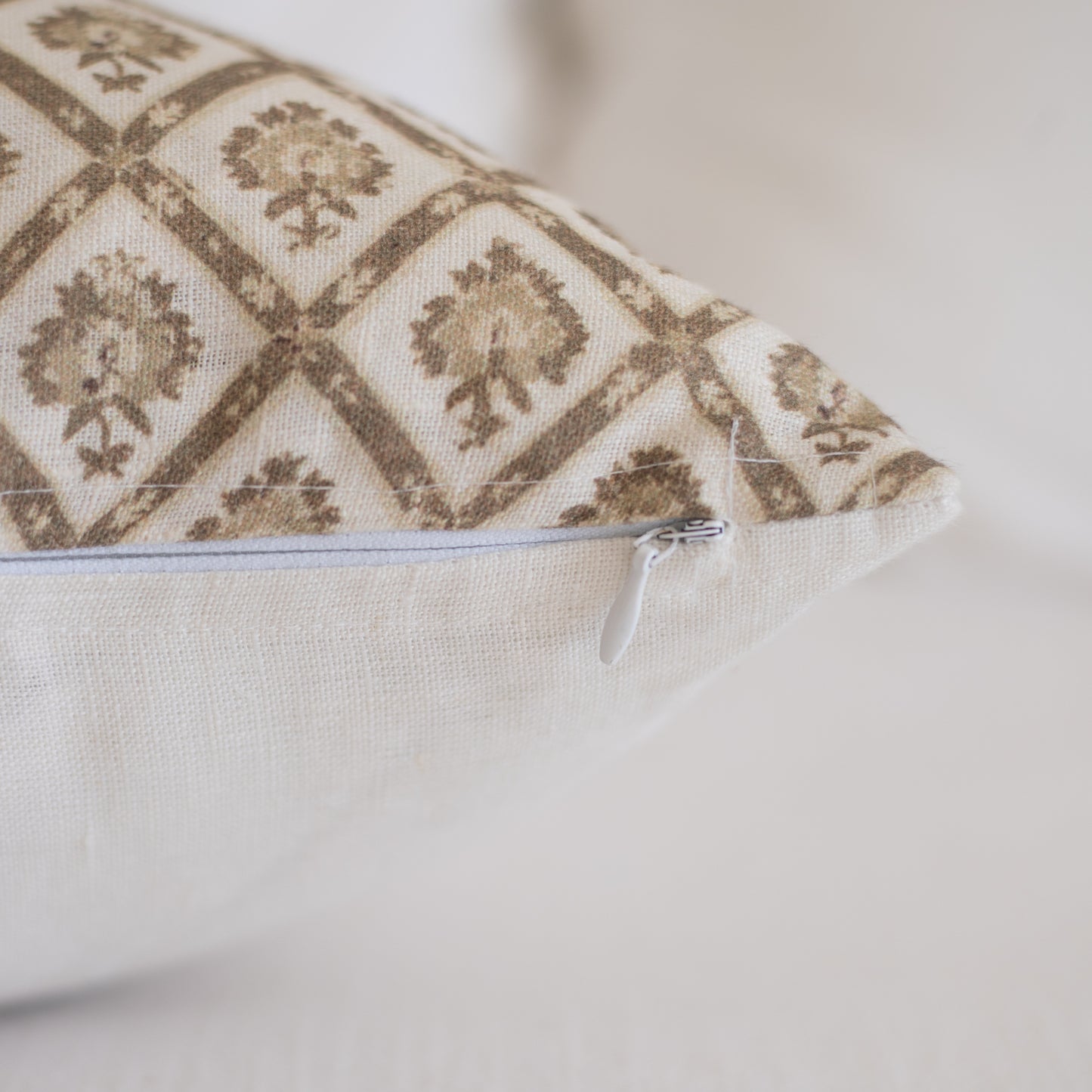 Linen lumbar pillow with tan and cream geometric damask pattern and white zipper closure.