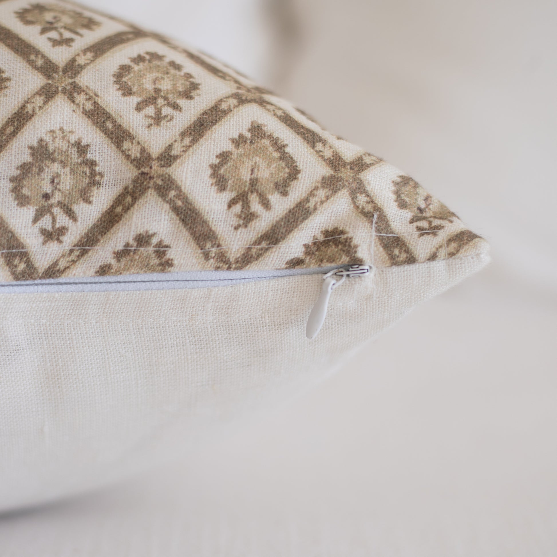 Linen lumbar pillow with tan and cream geometric damask pattern and white zipper closure.