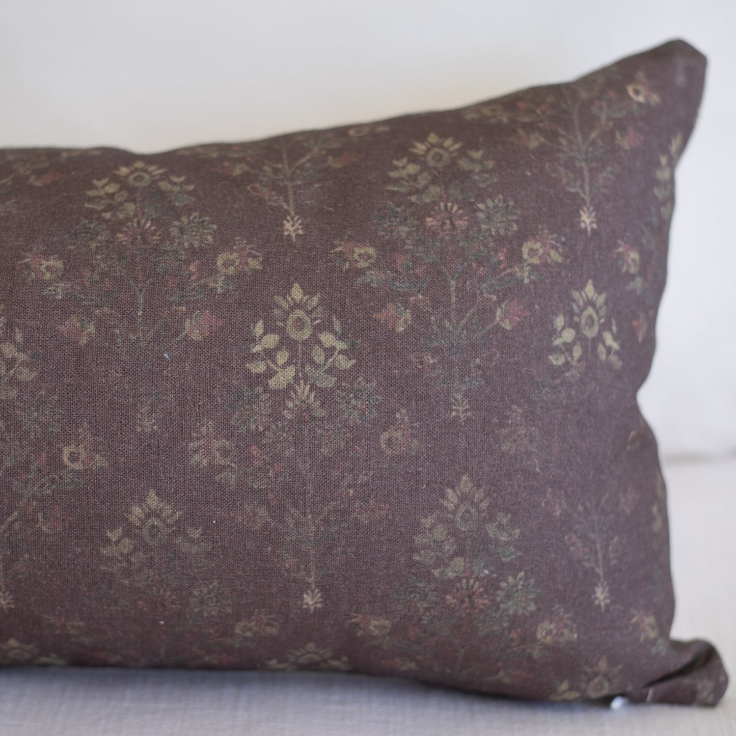 Burgundy linen pillow with small-scale floral and geometric pattern in muted gold tones.