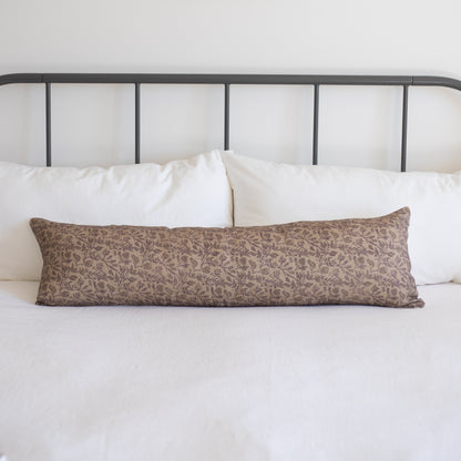 Long rectangular body pillow with taupe floral damask pattern on white bedding with metal headboard.
